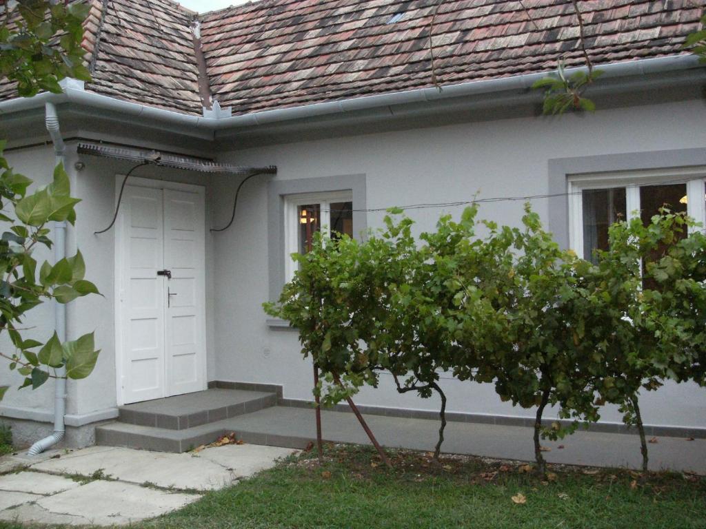 a white house with a white door and a tree at 98 Petőfi utca in Balatonmagyaród