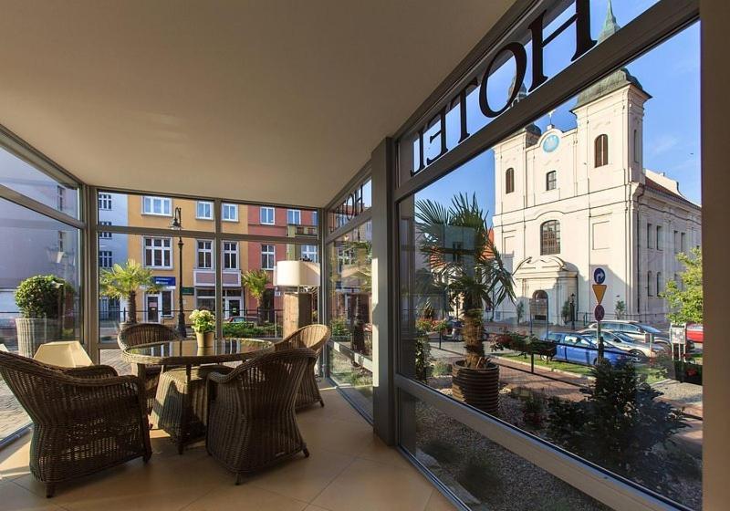 Habitación con ventana grande con mesa y sillas. en Hotel Ratuszowy, en Chojnice