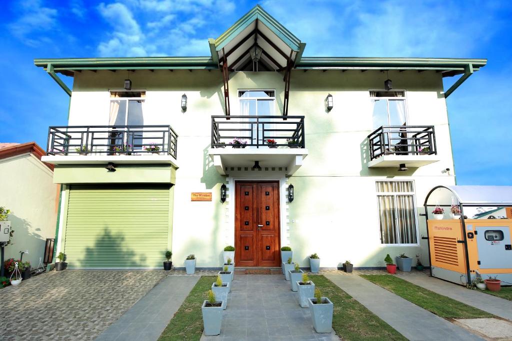 a white house with a red door and stairs at The Hamlyn in Nuwara Eliya