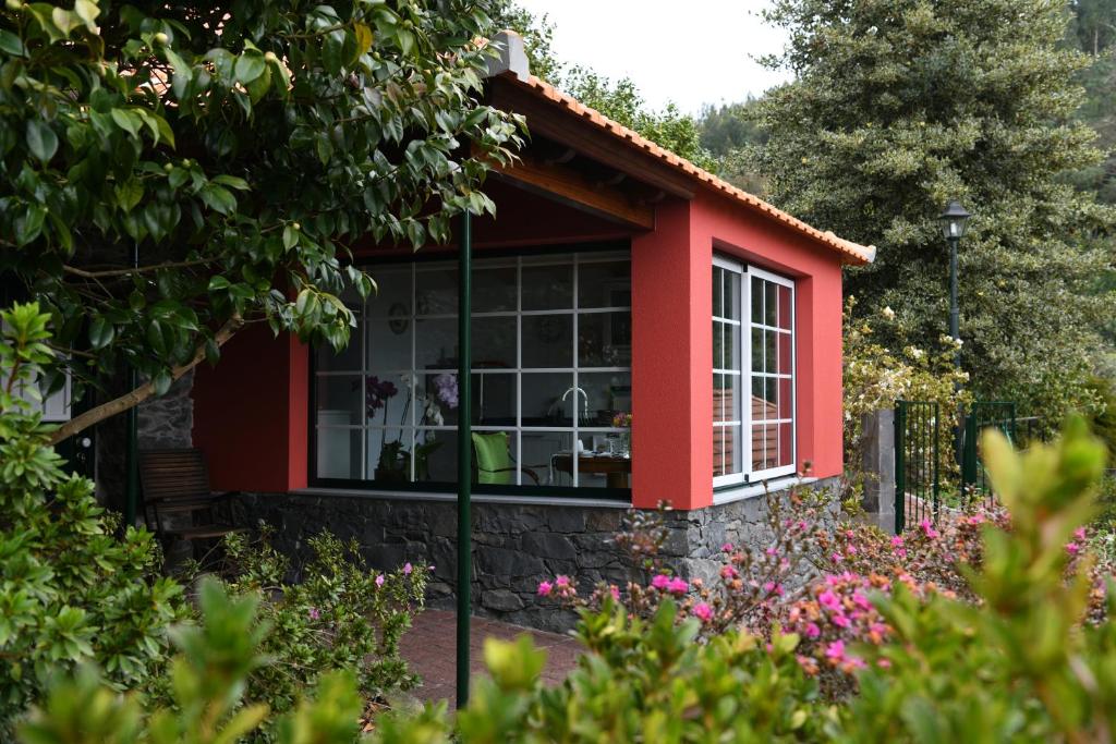 ein rotes Cottage mit einem Garten in der Unterkunft Casas de Pedra in Camacha