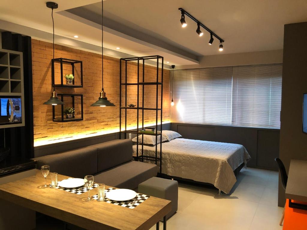 a bedroom with a bed and a table and a dining room at Estudio completo no coração do Batel in Curitiba