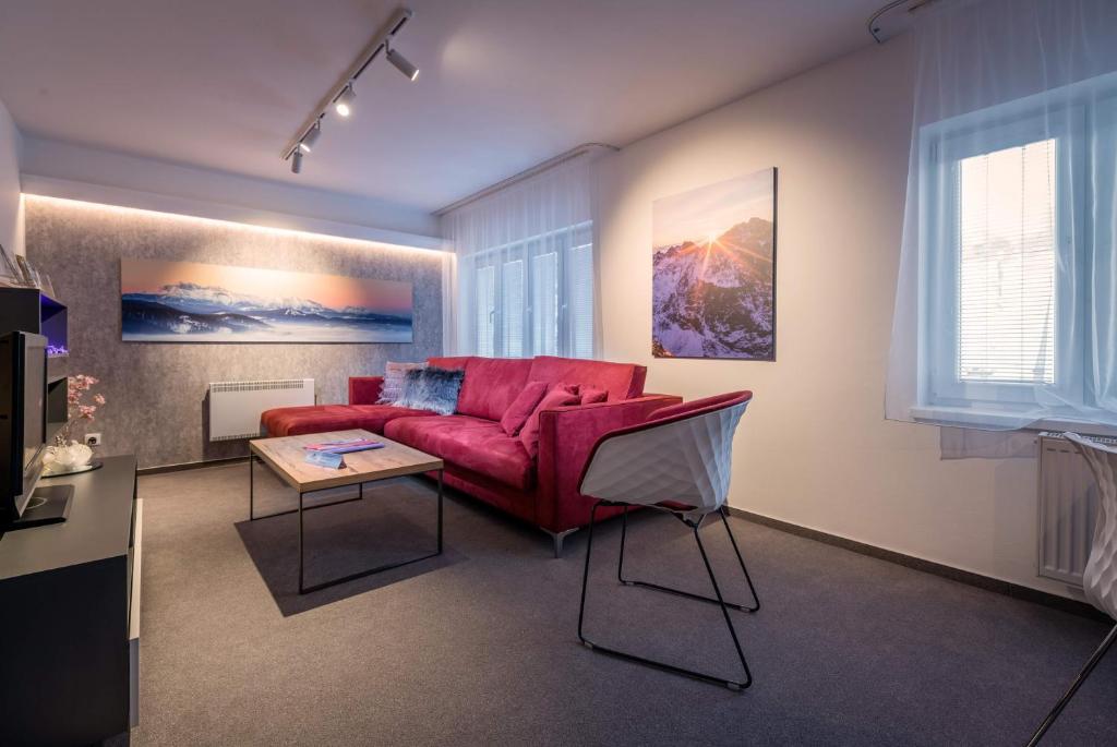 a living room with a red couch and a table at Apartman Smokovec in Vysoke Tatry - Novy Smokovec