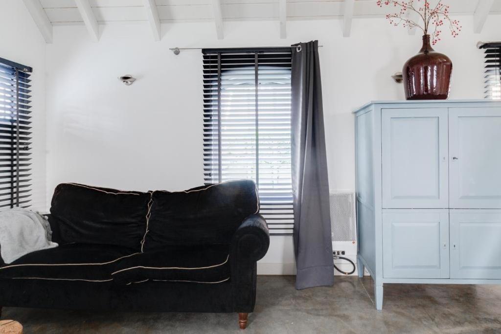 a living room with a black couch and a cabinet at Erve de Bakker op Westerflier in Markelo