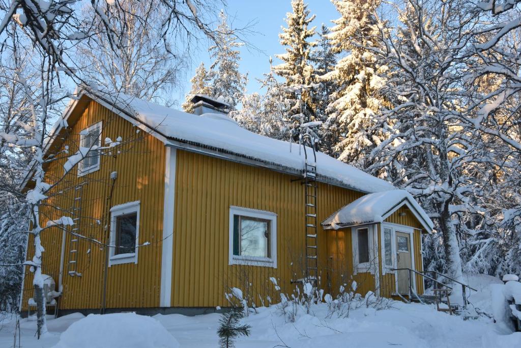 una cabaña en el bosque con nieve en el techo en Old wooden house 20 min from Koli, en Tuopanjoki