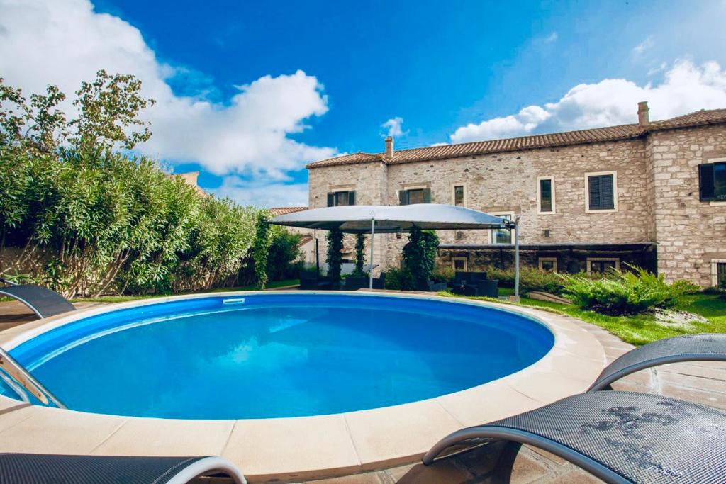 uma grande piscina azul em frente a um edifício em Borgo Antico XIX sec. em Gesturi