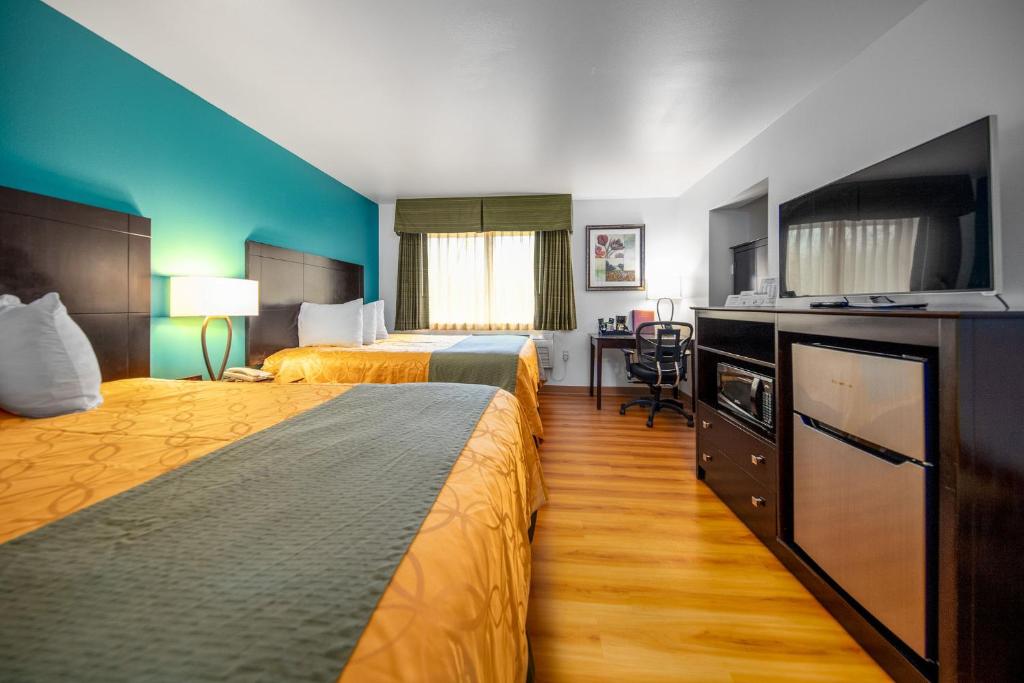 Habitación de hotel con 2 camas y TV de pantalla plana. en Sunset Motel Hood River en Hood River
