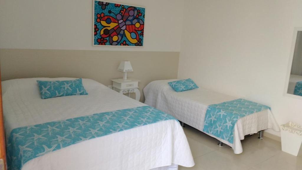 1 dormitorio con 2 camas y un cuadro en la pared en Pousada Bela Pinheira, en Palhoça
