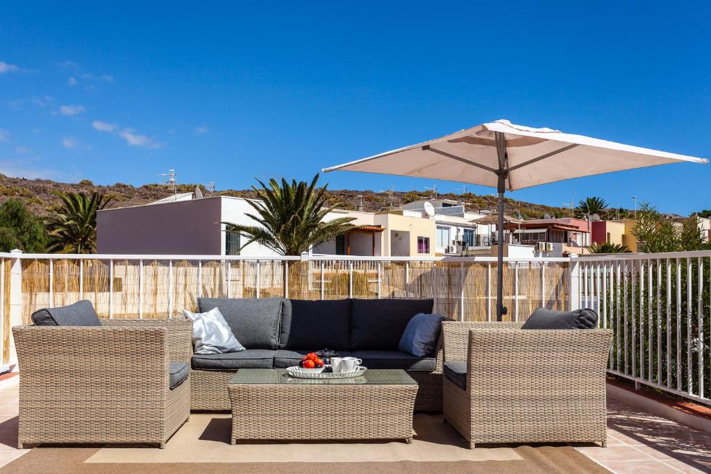 a patio with a couch and chairs and an umbrella at Cielo Azul in La Tejita