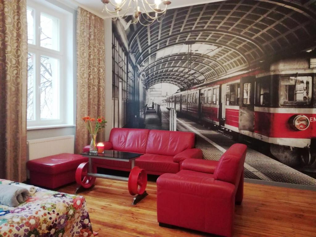 a living room with a red couch and a train mural at Stylowa Kamienica w Centrum in Olsztyn