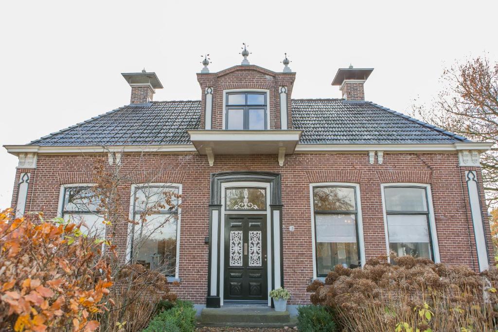 a red brick house with a black door at De Friese Wouden in Suameer
