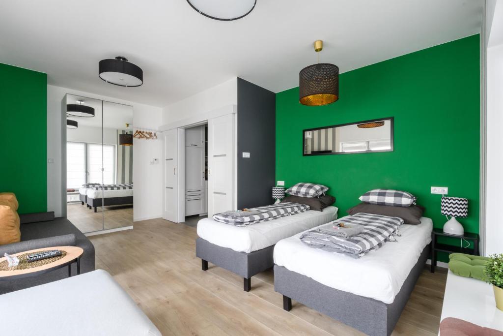ワルシャワにあるLabo Apartment Dzialdowskaの緑の壁のリビングルーム(ベッド2台付)