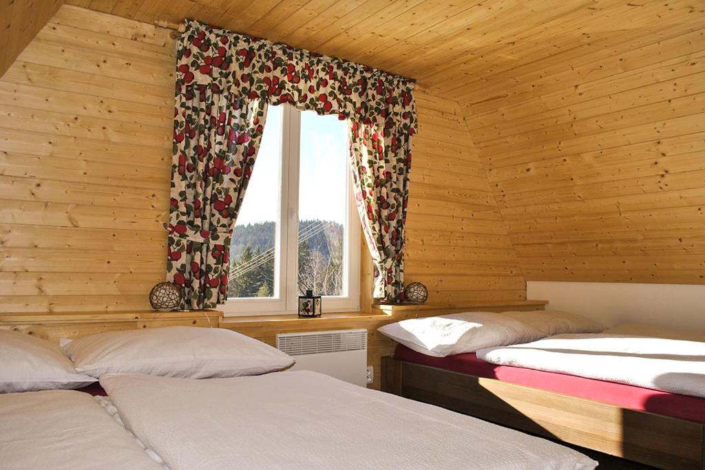 2 łóżka w drewnianym pokoju z oknem w obiekcie Chaty Pohoda na Soláni w mieście Velké Karlovice