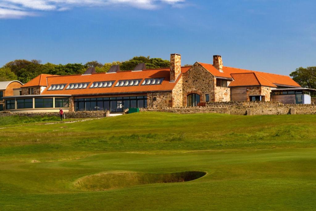 un campo de golf con un edificio en el fondo en The Lodge at Craigielaw and Golf Courses, en Aberlady