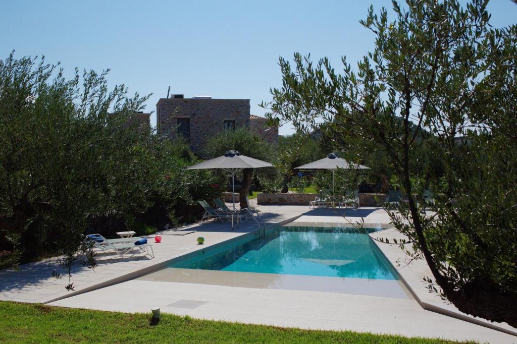 a swimming pool with chairs and umbrellas at Mythies - Holiday Houses in Mani in Levktron