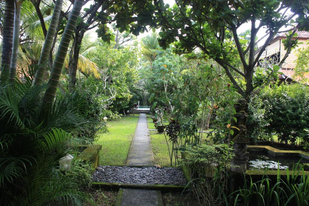 a garden with a bench and a tree at Villa Bhuana Alit in Ubud