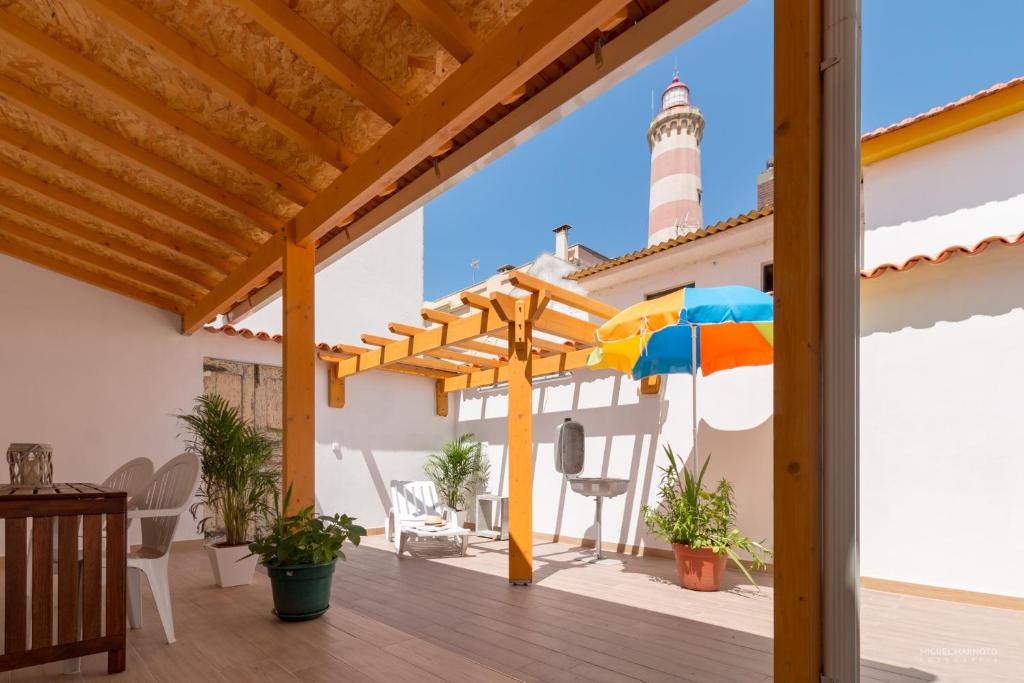 a patio with a lighthouse and a colorful umbrella at Vivenda Golfinho Barra in Praia da Barra