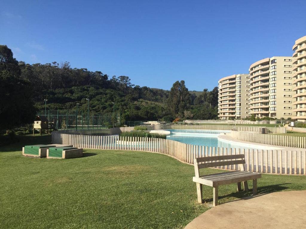 a bench sitting in the grass next to a pool at Departamento Costa Puyai II 751 in Papudo