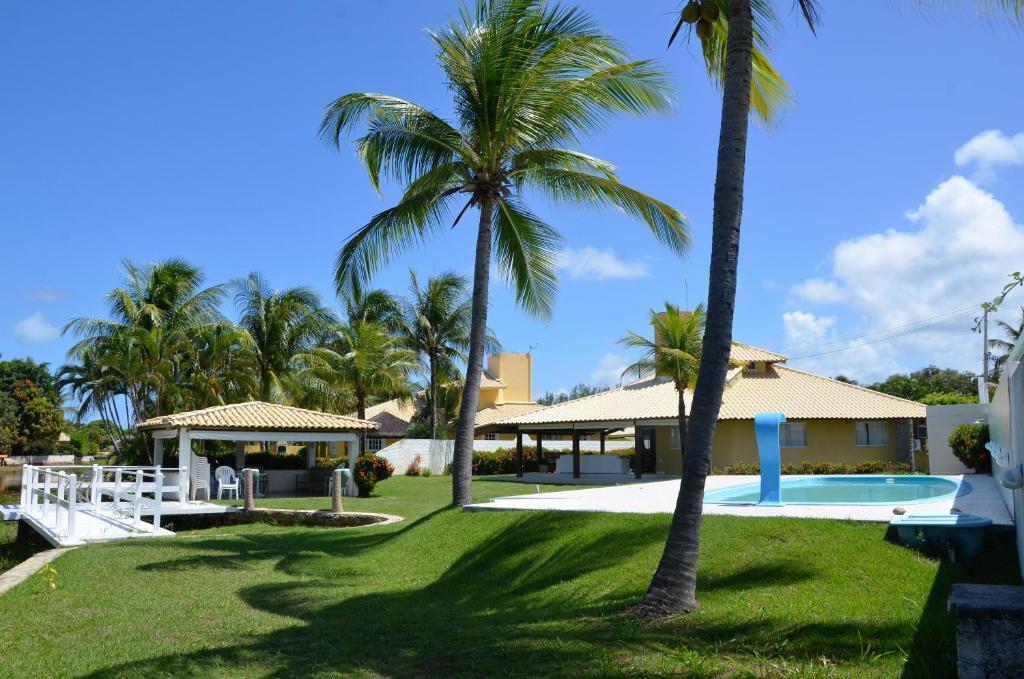 a resort with a swimming pool and palm trees at LINDA CASA 4 QUARTOS CONDOMÍNIO PARQUE INTERLAGOS in Arembepe