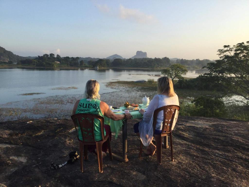 zwei Frauen sitzen an einem Tisch an einem Fluss in der Unterkunft Sigiri Lake Paradise in Sigiriya