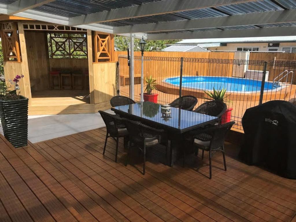 een patio met een tafel en stoelen en een zwembad bij Mill Corner Studios in Matamata