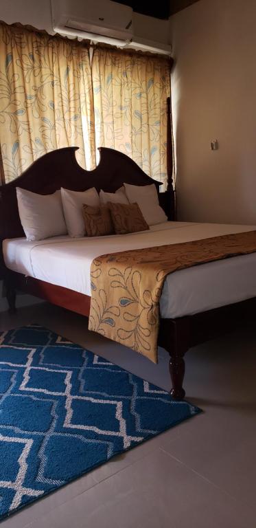 a bedroom with a large bed with a blue rug at Moonrisevillas in Negril