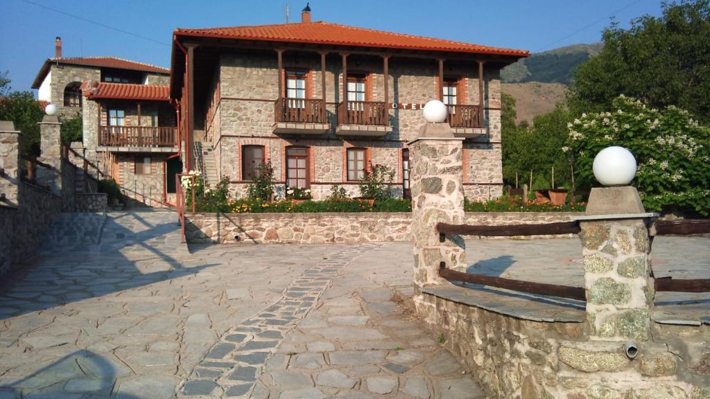 a stone house with a fence in front of it at Varnous Hotel in Agios Germanos