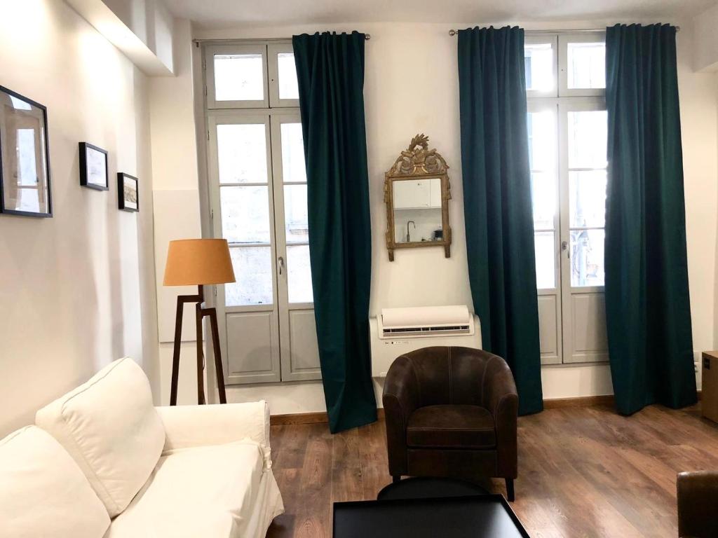 ein Wohnzimmer mit grünen Vorhängen und einem Stuhl in der Unterkunft Le musée Fabre, climatisation , parking gratuit in Montpellier