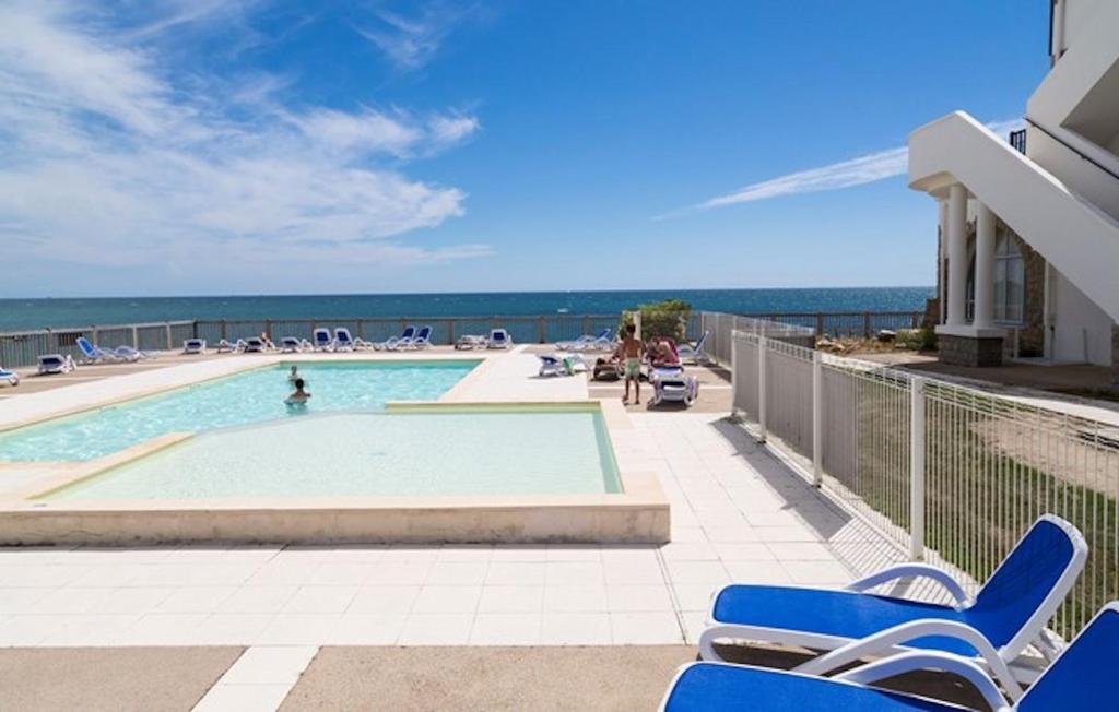 una piscina con sedie e l'oceano sullo sfondo di T2 Duplex Valentin Plage a Batz-sur-Mer
