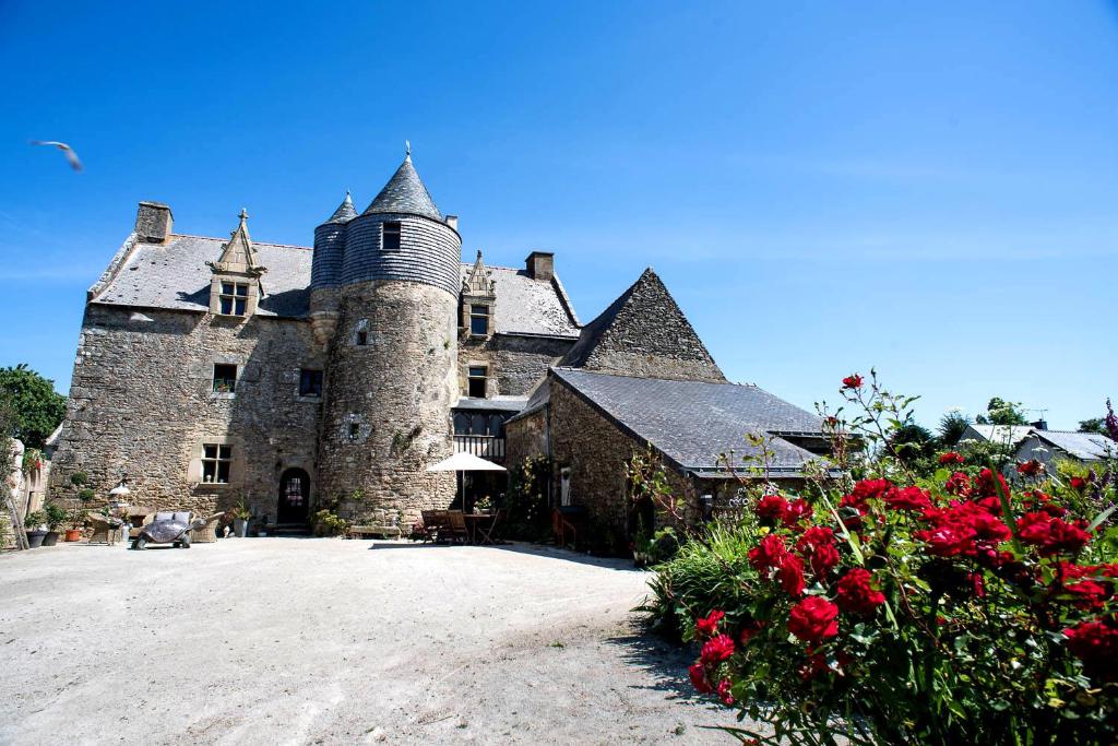 um velho castelo com flores vermelhas em frente em Manoir de la Sénéchaussée de Lantiern em Arzal