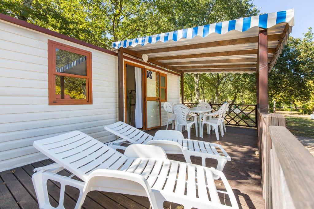 una terraza con sillas y mesas blancas y una pérgola en Albatross Mobile Homes on Camping Bijela Uvala, en Poreč