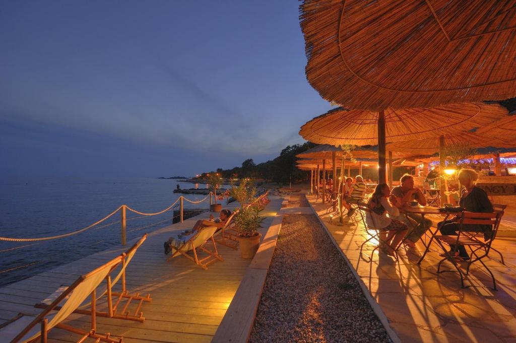 a group of people sitting on a deck near the water at Albatross Mobile Homes on Camping Bijela Uvala in Poreč