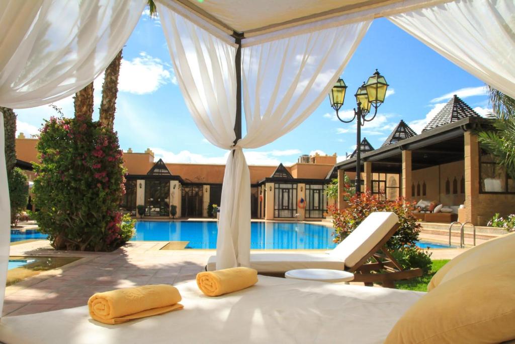 a bed with two yellow pillows on a bed in front of a pool at Berbère Palace in Ouarzazate