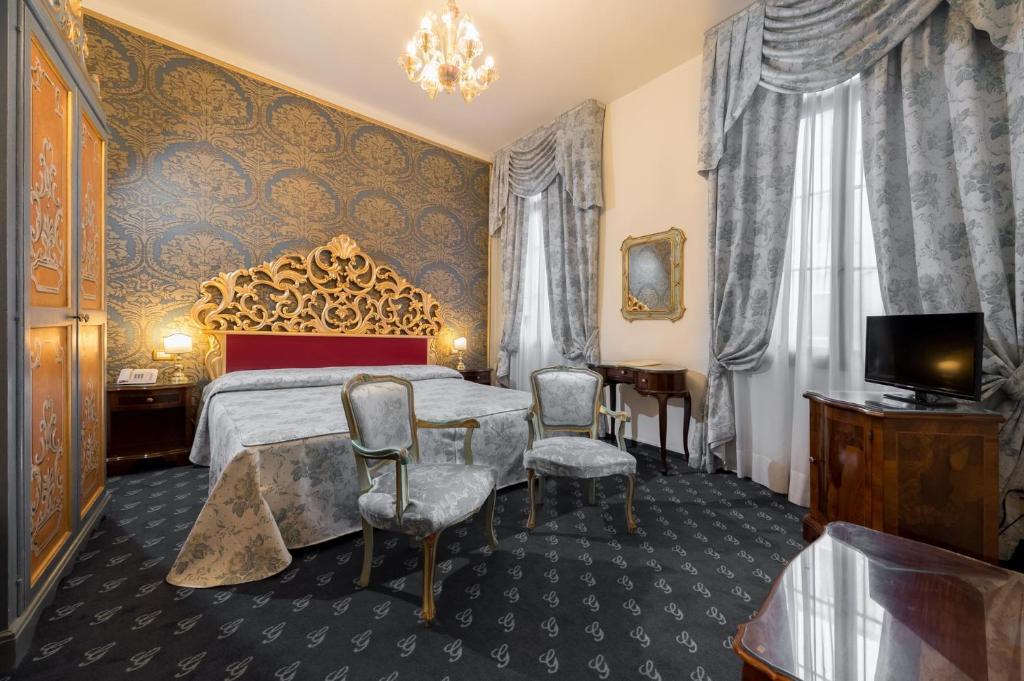 a bedroom with a bed and chairs and a television at Hotel Giorgione in Venice