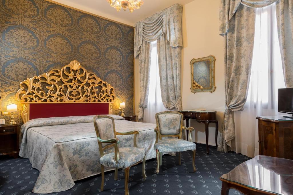 a bedroom with a bed and two chairs at Hotel Giorgione in Venice