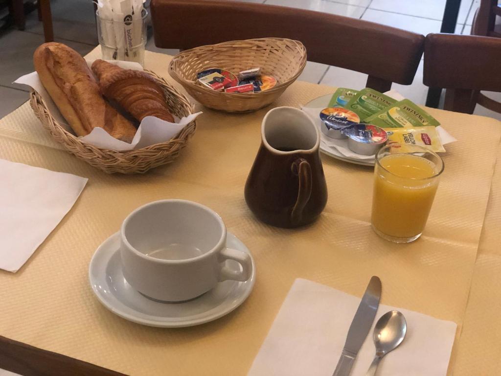 a table with a cup of coffee and a basket of bread at Hotel Liberty in Paris