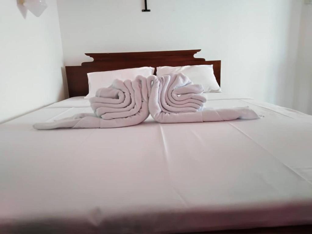 a white bed with two white pillows on it at The Finz in Hikkaduwa