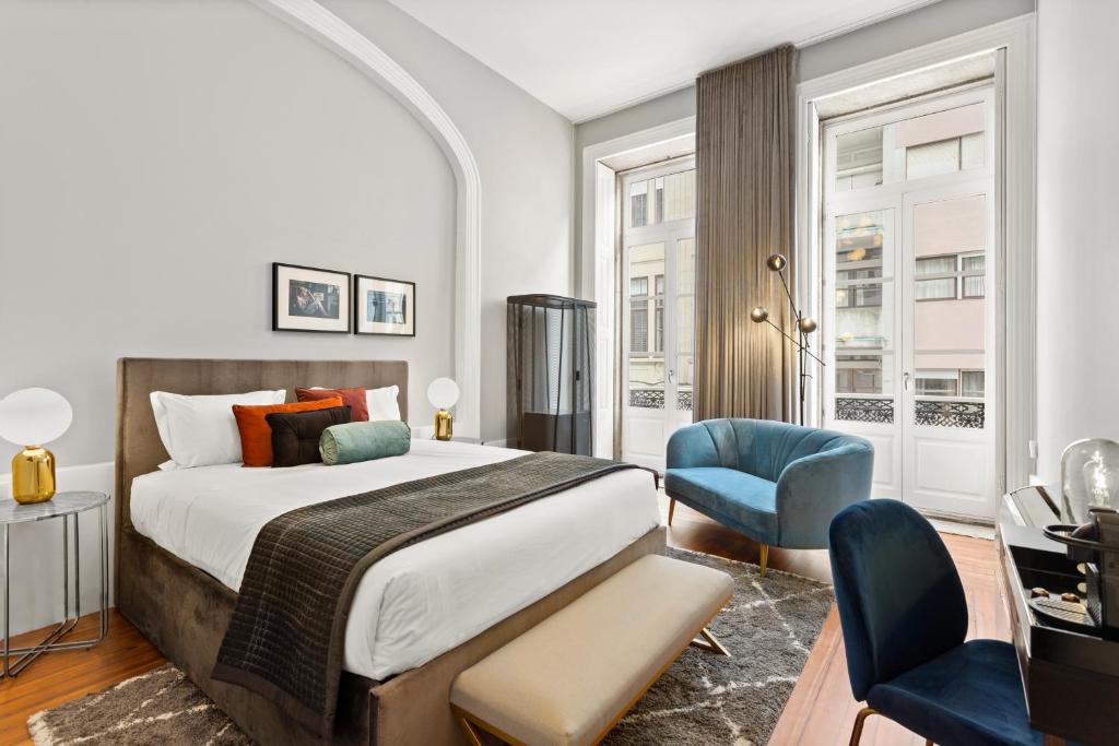 a bedroom with a large bed and a blue chair at The White Box Boutique House in Porto