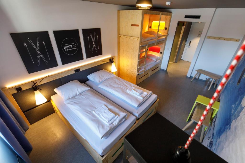 Cette petite chambre comprend deux lits et une table. dans l'établissement DJH moun10 Jugendherberge - membership required!, à Garmisch-Partenkirchen