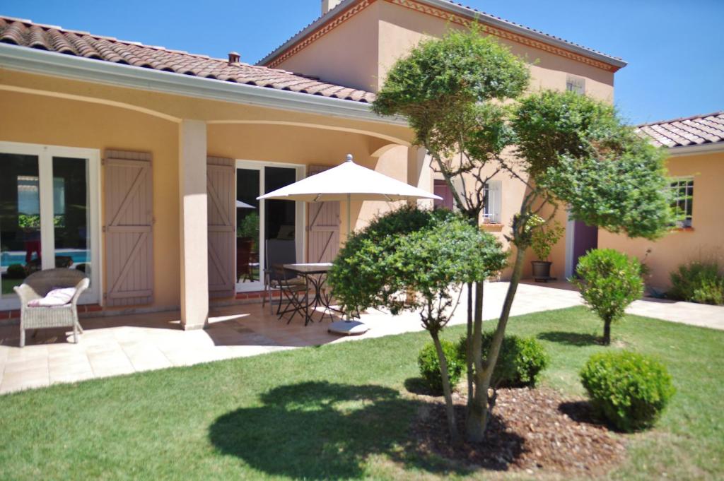 a patio with a table and an umbrella in a yard at La Lilas des Fargues Maison d'Hôtes in Albi