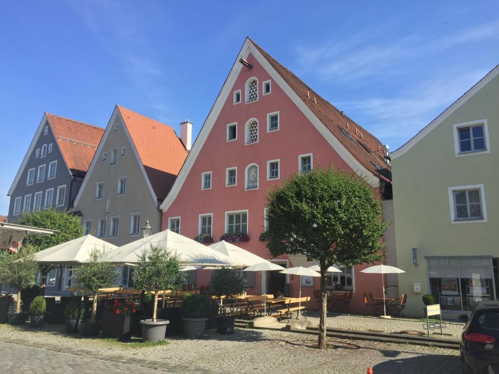 szereg kolorowych budynków ze stołami i drzewami w obiekcie Hotel-Gasthof Blaue Traube e.K. w mieście Berching