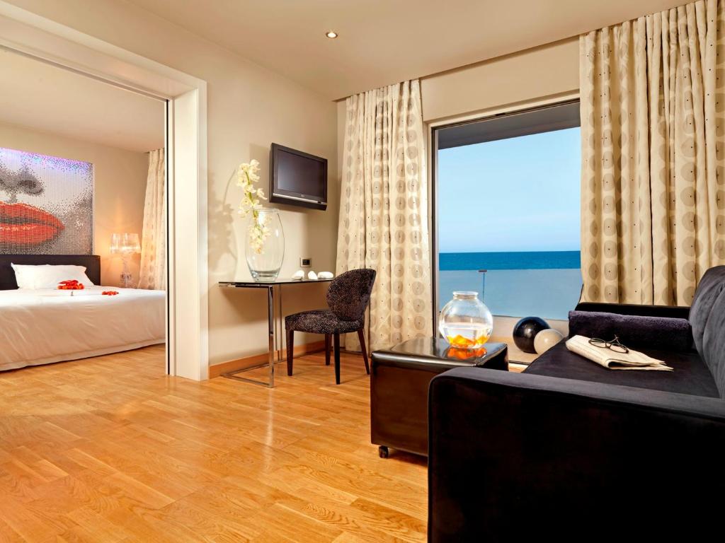 a hotel room with a bed and a desk and a window at Out Of The Blue Resort & Spa in Agia Pelagia