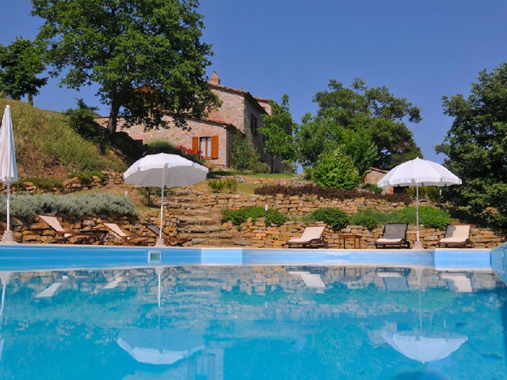 a swimming pool with umbrellas and chairs and a house at Spacious Villa in Ficulle with Pool in Ficulle