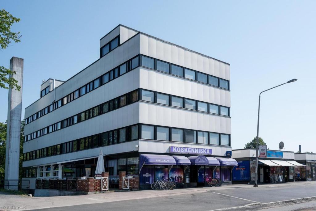 a tall white building with a store in front of it at Hotelli Koskenniska in Forssa