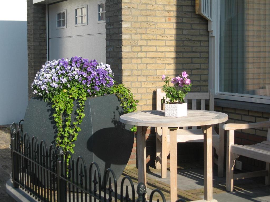 a patio with a table and flowers on a fence at De Oosterberg in Egmond aan Zee