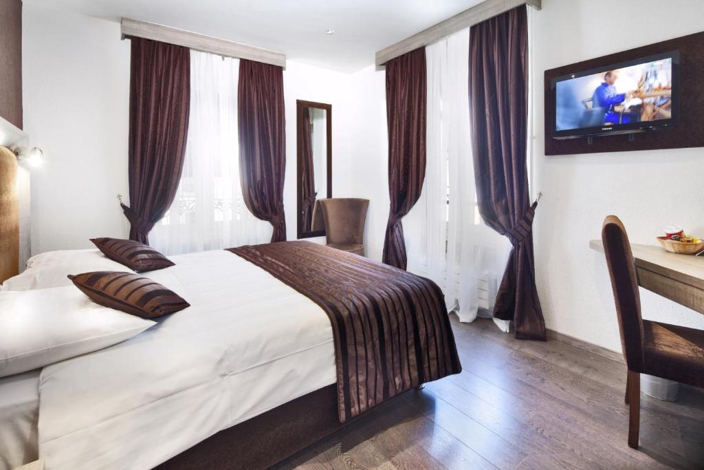 a bedroom with a bed and a tv on the wall at Hotel Strasbourg in Geneva