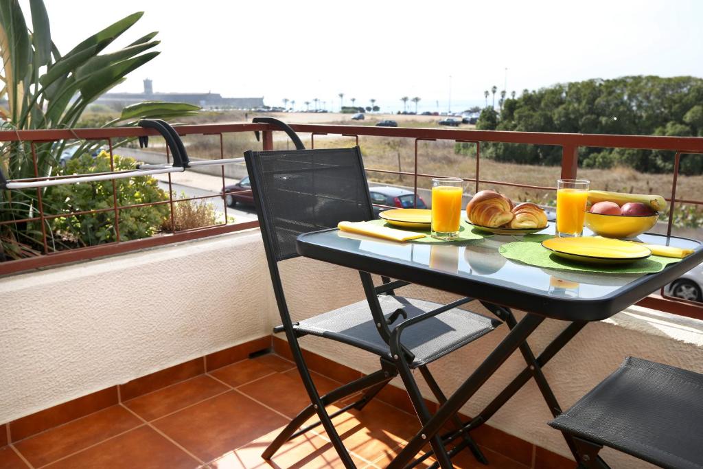 a table with food and orange juice on a balcony at Like-home Sea View Apt in Carcavelos