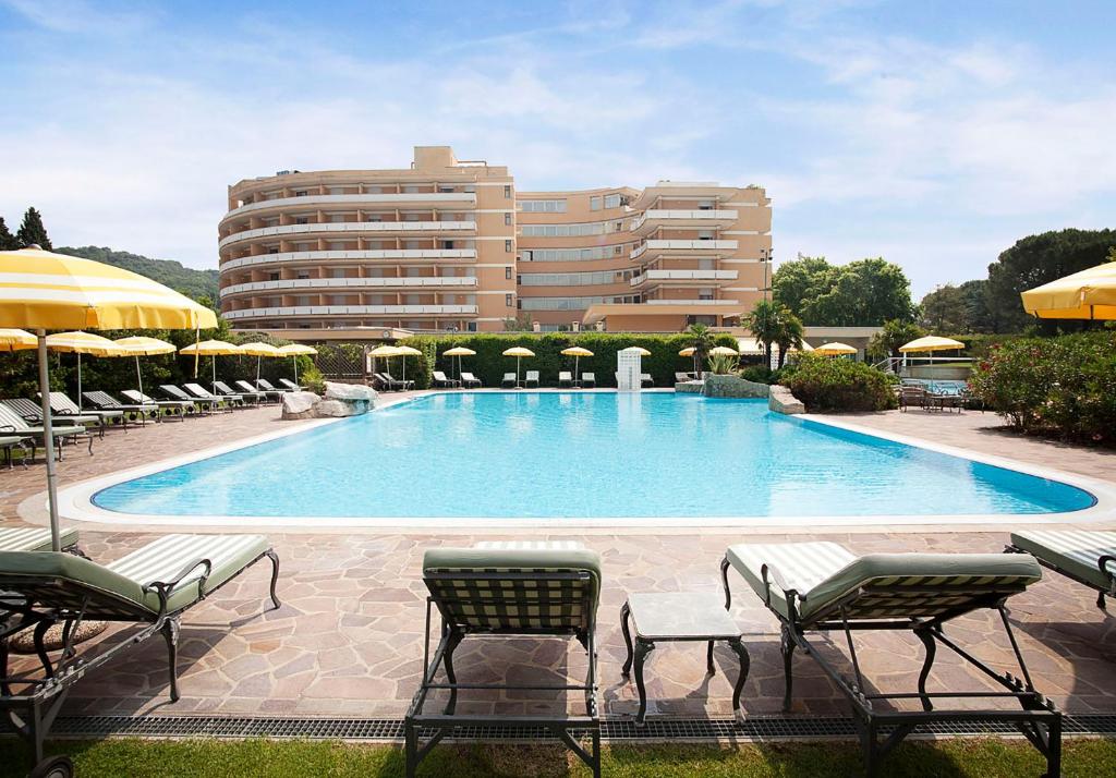 ein großer Pool mit Stühlen und ein Gebäude in der Unterkunft Hotel Sporting Resort in Galzignano Terme