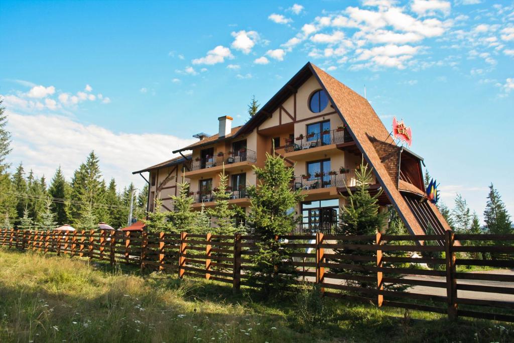 a house with a fence in front of it at Complex Turistic Le Baron in Vatra Dornei