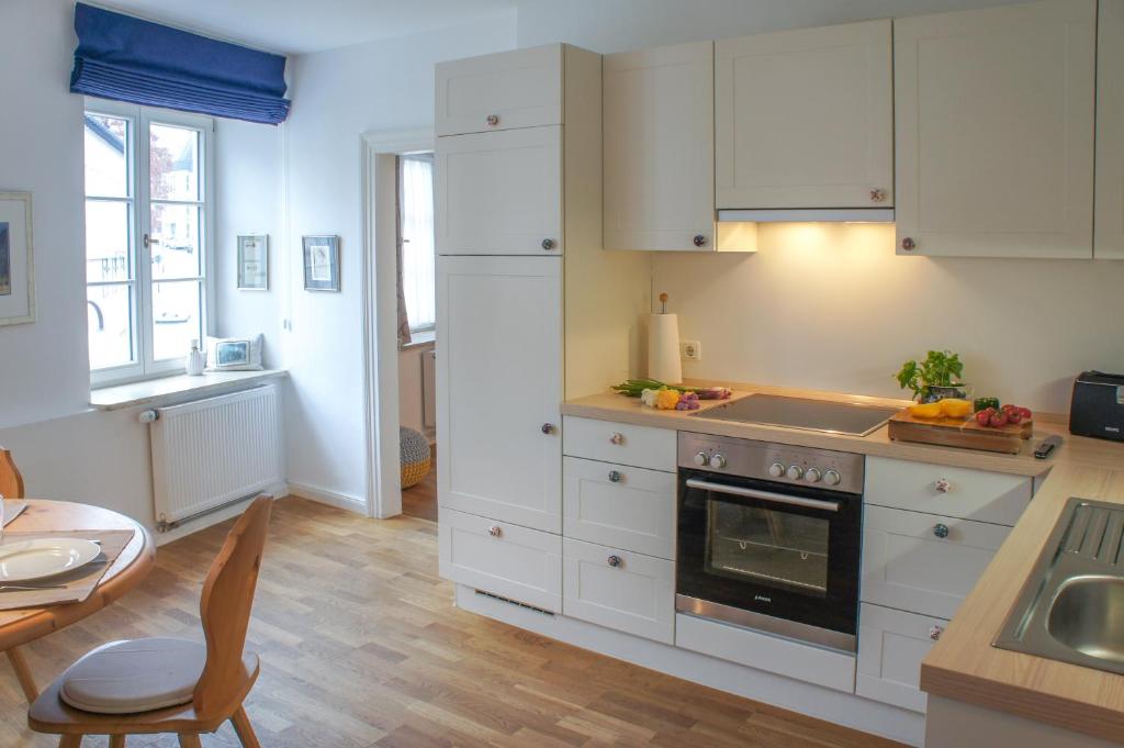 a kitchen with white cabinets and a stove and a table at Bad Tölz Mittendrin in Bad Tölz