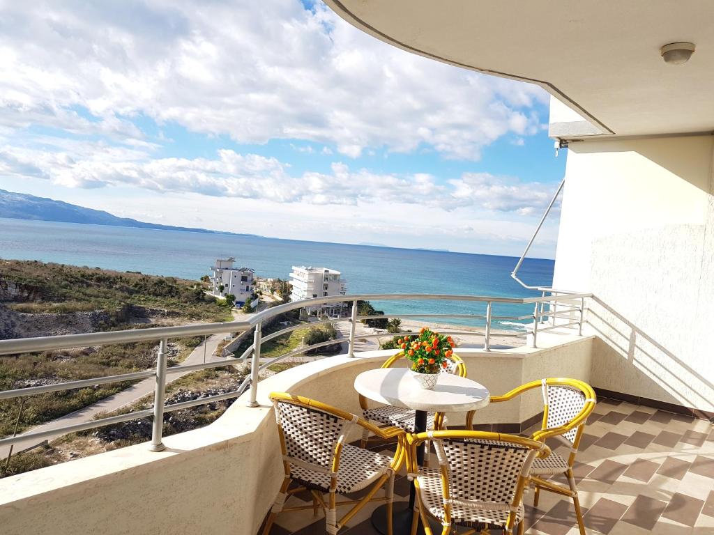 uma varanda com uma mesa e cadeiras e o oceano em Exotic Apartment em Saranda